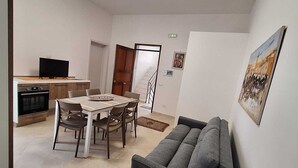 A modern living room with a sofa, dining table, and kitchen area. - Il Lentisco (Lecce)