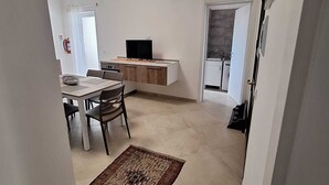 A modern apartment with a dining area, a kitchen with a TV, and a living area. - Il Lentisco (Lecce)