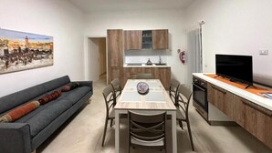 A compact living space with a dining table, sofa, kitchenette, and a television. - Il Lentisco (Lecce)