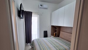 A bedroom with a bed, an air conditioning unit, a TV, and a wardrobe. - Il Lentisco (Lecce)