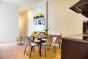 A modern dining area with a table, chairs, a sofa, and a small side table with a plant.