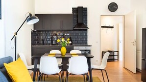 Een moderne keuken met zwarte kasten, een zwart fornuis en een klok aan de muur.