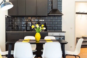 A modern kitchen with black cabinets, a black countertop, and a yellow vase with flowers.