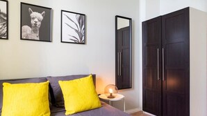 Een slaapkamer met een bed, twee kussens, een bedlampje, een kledingkast en ingekaderde foto's aan de muur.