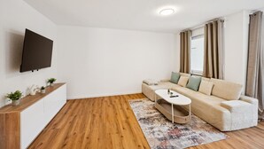 A modern living room with a sofa, coffee table, and a flat-screen TV mounted on the wall.