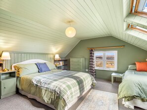 A bedroom with a bed, bedside tables, a window with a view, a lamp, and a bookshelf.