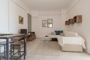 A compact living space with a desk, a sofa, a coffee table, and a TV. - MelMare Azuro Apartment by RentalsPro (Nea Moudania)