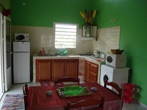 A compact kitchen with a dining area, a refrigerator, a microwave, and a sink.