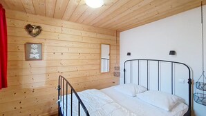 A wooden-paneled room with a bed, a heart-shaped decoration, a framed picture, and a hanging light fixture. - Chalet le Cairn CRN CENTER & TELECABINE 10 Pers. (Châtel)