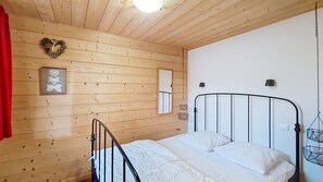 Ein Zimmer mit Holzwänden, einem Bett, einer herzförmigen Dekoration, einem gerahmten Bild und einer Pendelleuchte.