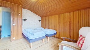 A room with two beds, a wooden ceiling, a stone wall, and a wooden door. - Chalet le Cairn CRN CENTER & TELECABINE 10 Pers. (Châtel)