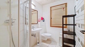 A bathroom with a shower, sink, toilet, and a wooden shelf. - Chalet le Cairn CRN CENTER & TELECABINE 10 Pers. (Châtel)