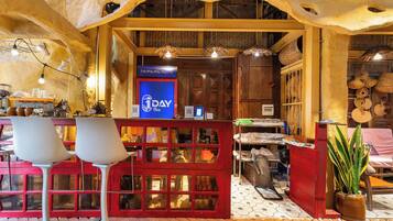 A restaurant interior with a red booth seating area, a blue sign with '1DAY Tea' text, and various kitchen utensils visible through the booth windows.