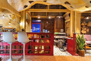 A restaurant interior with a red booth seating area, a blue sign with '1DAY Tea' text, and various kitchen utensils visible through the booth windows. - Oxy homestay Mui Ne (Mui Ne)
