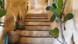 Un escalier avec un mur à texture, des paniers et des plantes vertes.