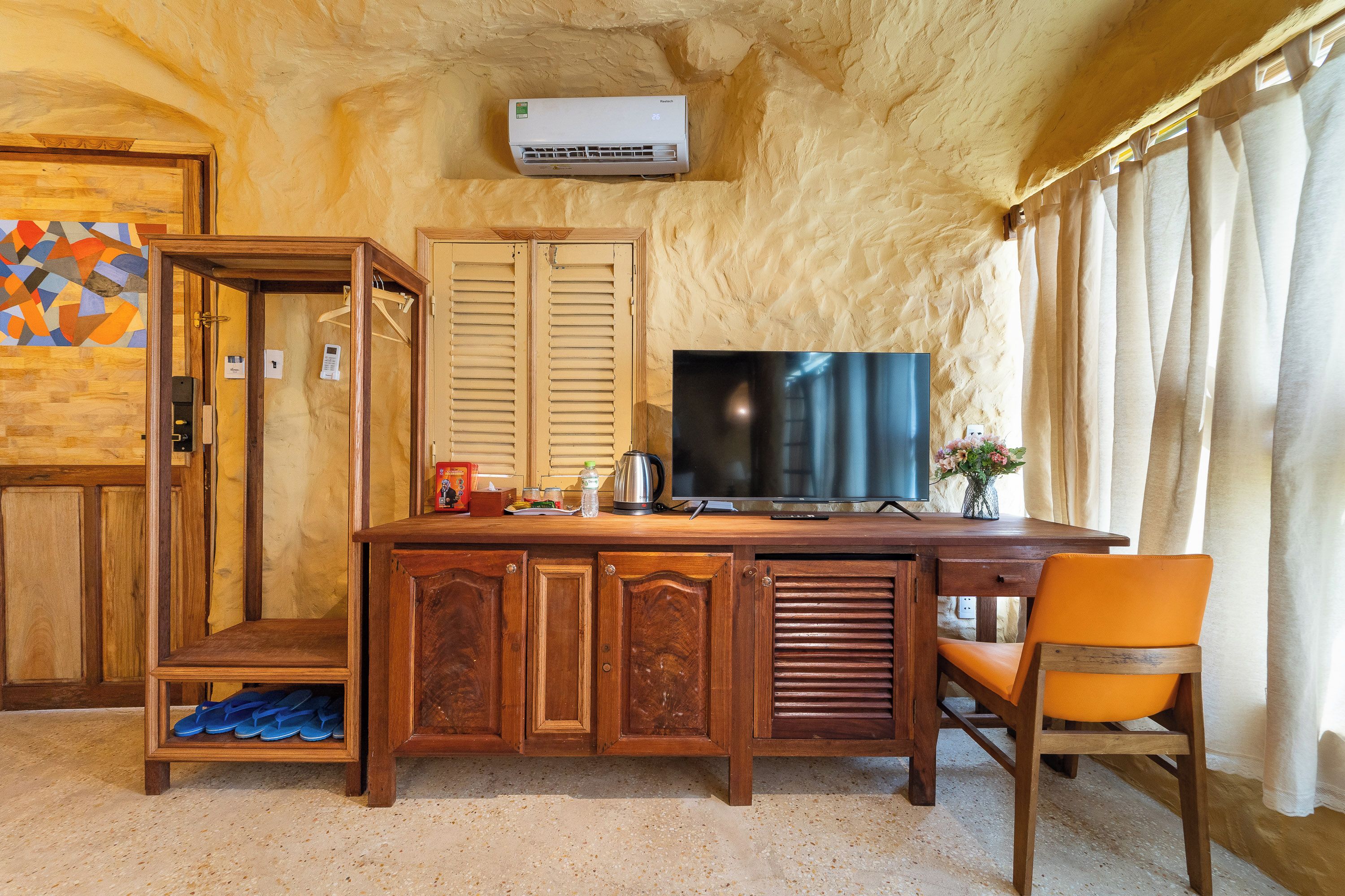A room with a wooden desk, a television, and a chair.