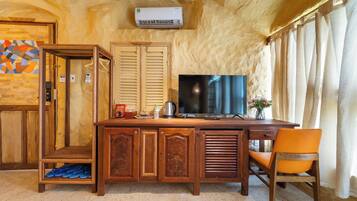 A room with a wooden desk, a television, and a chair.