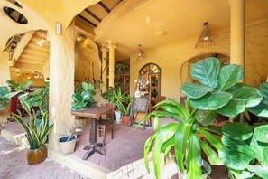 An indoor courtyard with brick flooring, potted plants, a wooden table, and a hanging light fixture. - Oxy homestay Mui Ne (Mui Ne)