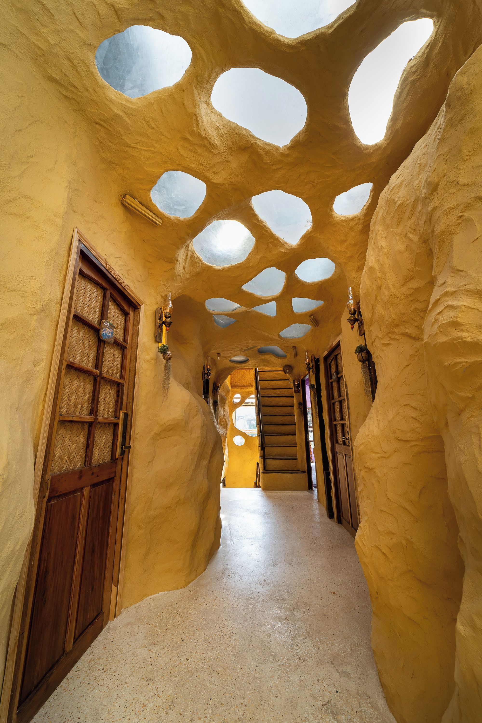 A hallway with a unique architectural design featuring rounded, cave-like structures and multiple circular openings on the ceiling.