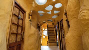 A hallway with a unique architectural design featuring rounded, cave-like structures and multiple circular openings on the ceiling.