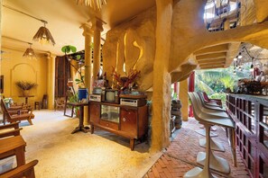 A room with wooden furniture, a bar area, and a view of greenery outside. - Oxy homestay Mui Ne (Mui Ne)