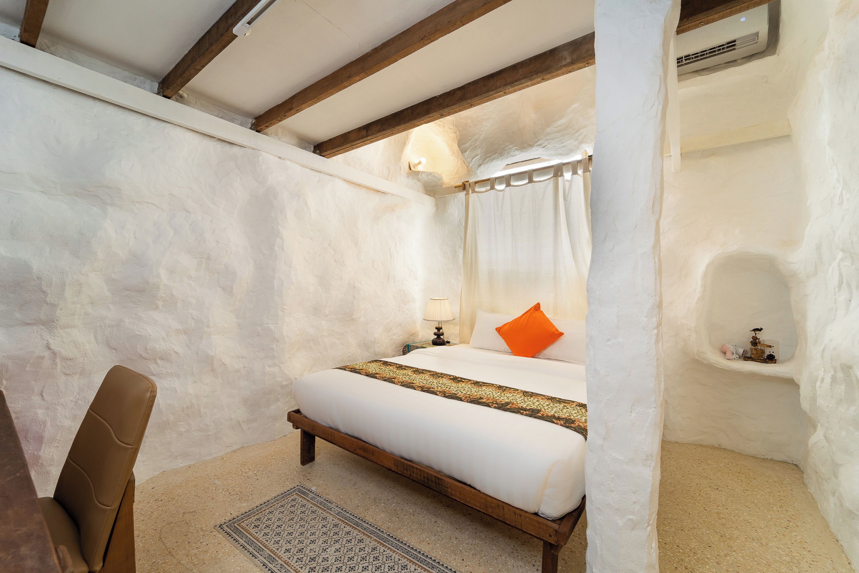 Una camera da letto con un letto, una sedia, un comodino e un condizionatore d'aria a muro.