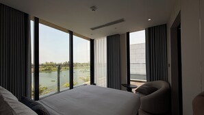 A modern hotel room with a large bed, a seating area, and a view of a river. - Luxury Villa Near My Khe Beach (Đà Nẵng)