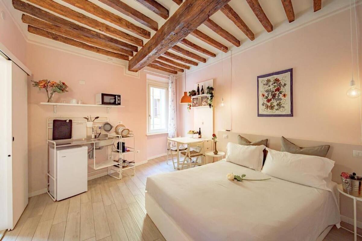 Un dormitorio con cama, mesita de noche y un pequeño escritorio con silla.