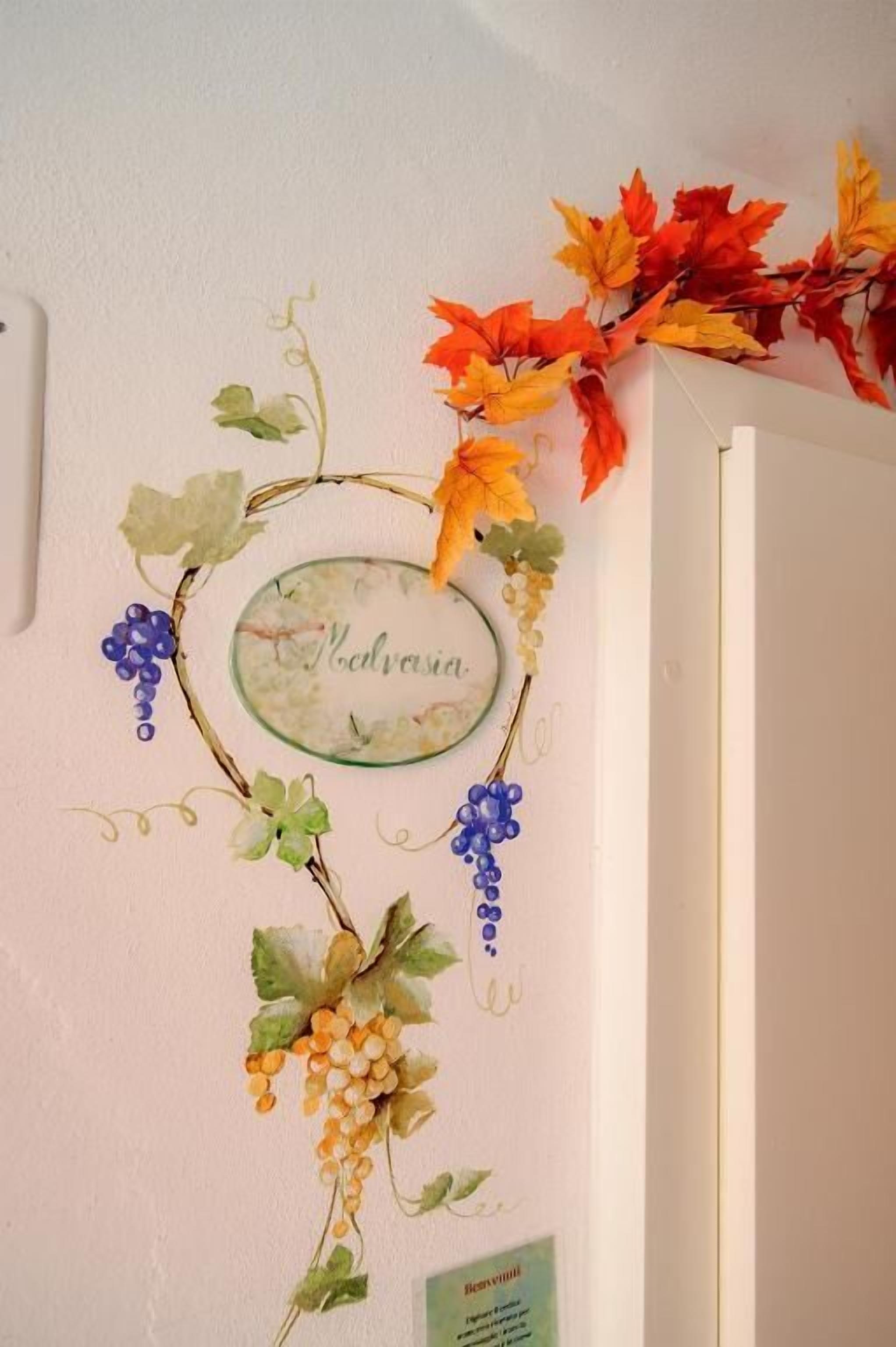 A wall with a decorative grapevine and autumn leaves, a nameplate, and a sign with text.