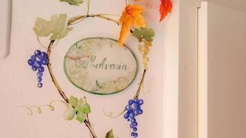 A wall with a decorative grapevine and autumn leaves, a nameplate, and a sign with text.