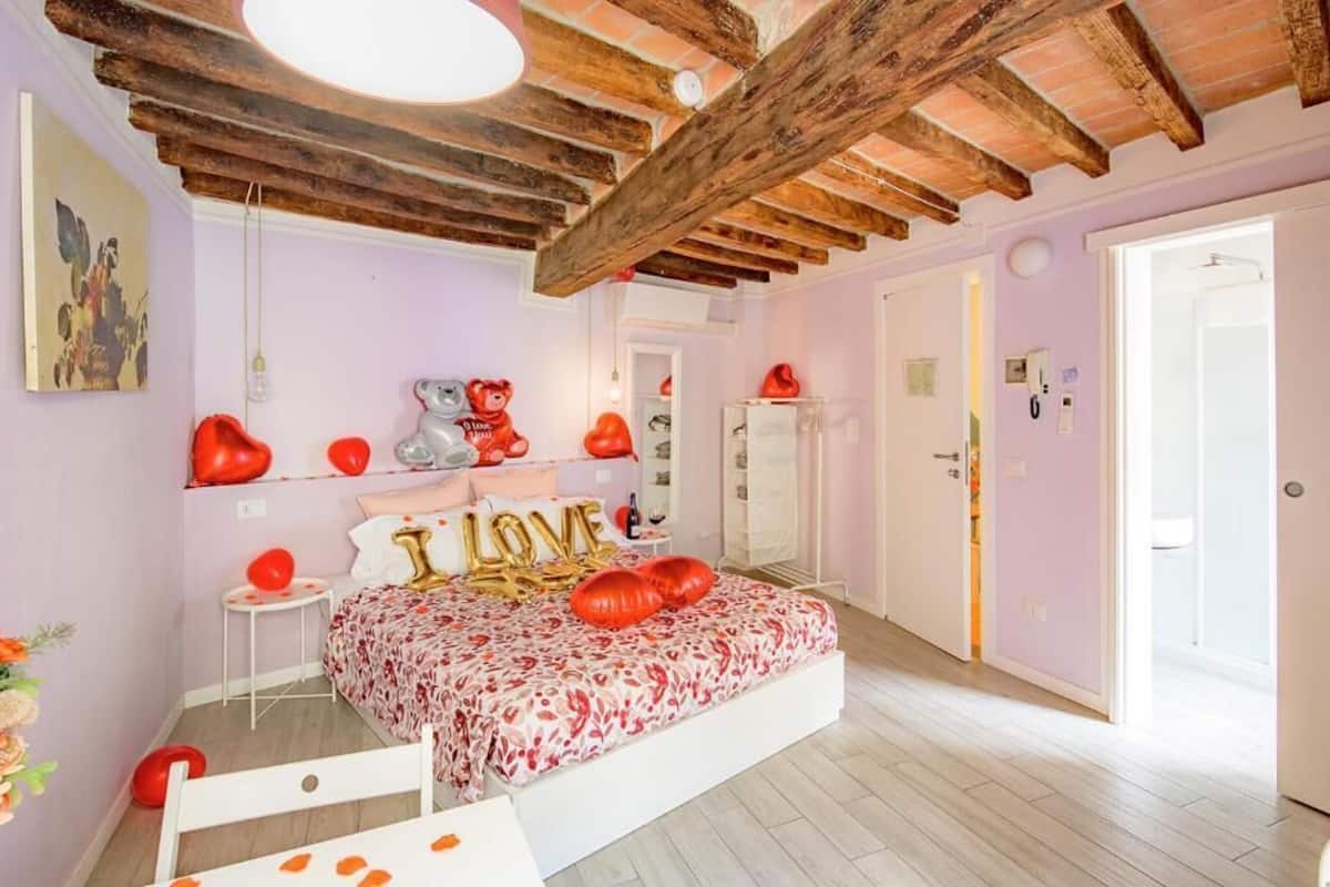 Un dormitorio con una cama, techo de madera, una puerta y un cuadro en la pared.