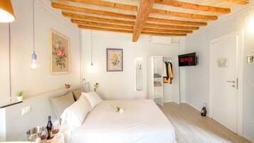 A bedroom with a wooden ceiling, a bed, a TV, a wardrobe, and a door.