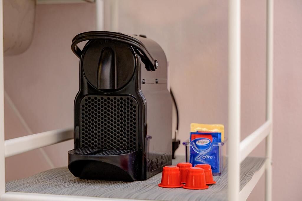 A coffee maker, a box of coffee pods, and red cups on a shelf.