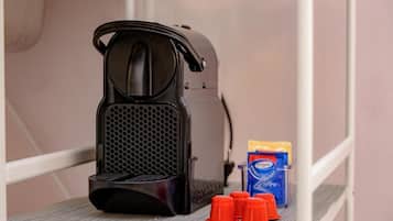 A coffee maker, a box of coffee pods, and red cups on a shelf.
