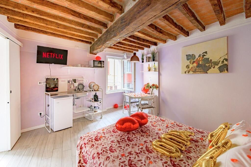 Een slaapkamer met een bed, een bureau, een televisie en een raam.