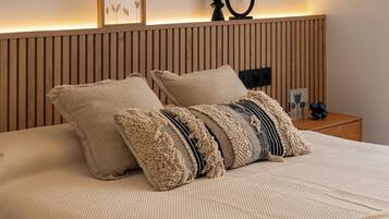 Un letto con due cuscini, una testiera in legno, un comodino con una lampada e una cornice appesa al muro.