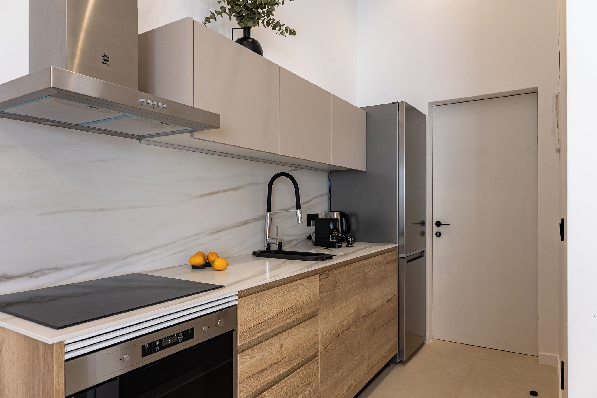 A modern kitchen with a built-in stove, a sink, and a refrigerator.