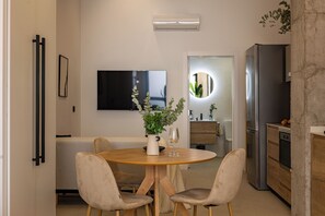 A modern kitchen with a dining area, a flat-screen TV, a refrigerator, and a potted plant on the table. - Almirante Suites (València)
