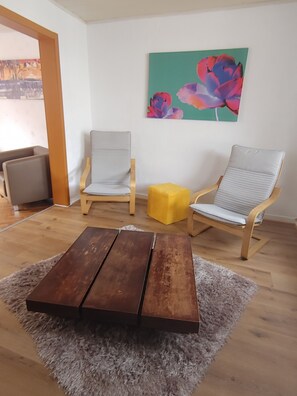 A room with two armchairs, a wooden coffee table, a small yellow ottoman, and a painting on the wall. - House in the heart of the old town (Rheinbach)