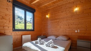 Habitació amb panells de fusta, un llit, taules de nit i una finestra amb vista.