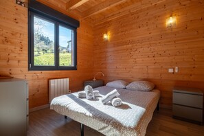 Una habitación con paneles de madera, una cama, mesitas de noche y una ventana con vistas.