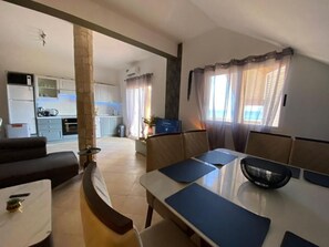 A modern living room with a dining area, kitchen in the background, and large windows with curtains. - La Vedetta Bella Vista Ocean View (Santa Maria)