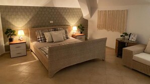 A bedroom with a bed, bedside tables, a nightstand, a sofa, and a wall-mounted tapestry. - La Vedetta Bella Vista Ocean View (Santa Maria)