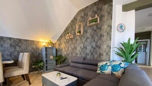 A modern living room with a sectional sofa, a coffee table, a dining area with chairs, a bookshelf, and a wall with built-in shelving. - La Vedetta Bella Vista Ocean View (Santa Maria)