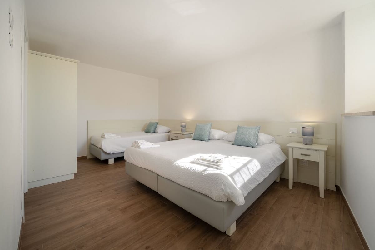 A bedroom with two beds, bedside tables, and a wardrobe.