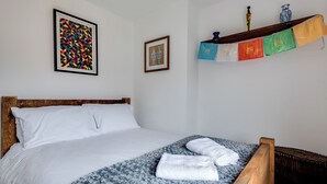 Ein ordentlich bezogenes Bett mit weißen Laken, einer blau-weißen Decke und zwei weißen Handtüchern.