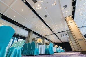 A banquet hall with rows of chairs, tables, and a ceiling with hanging lights. - Zhonghui Hotel (Anji)