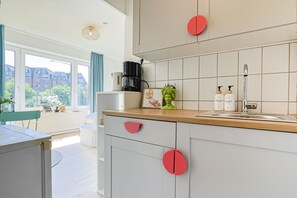 A modern kitchen with a large window, a coffee maker, and a sink.