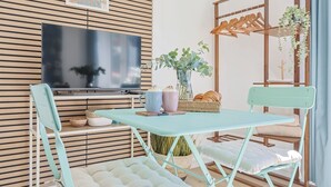 Una habitación con una mesa plegable, dos sillas, un televisor, una planta y un panel de pared de madera.