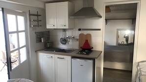 Kompakti keittiö, jossa on valkoiset kaapit, sisäänrakennettu liesi ja pesuallas.
